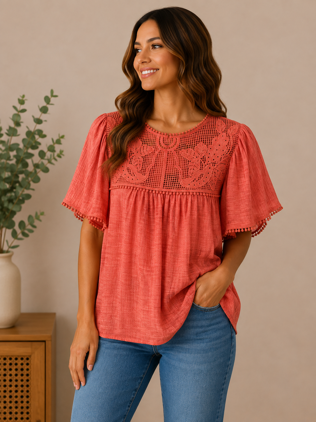 Woman wearing the sunset bloom lace-yoke blouse in coral.